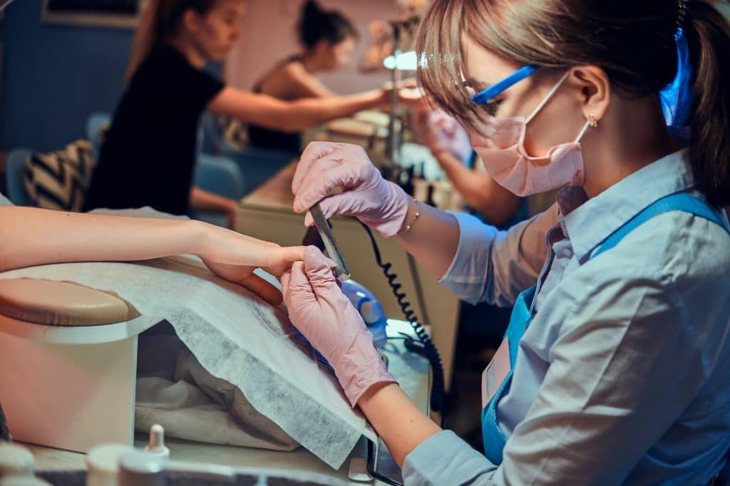 Nail treatment process at busy manicure salon.