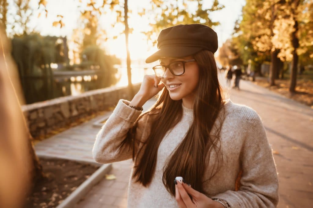 Beautiful young girl listening to music in the park through a wireless earpiece