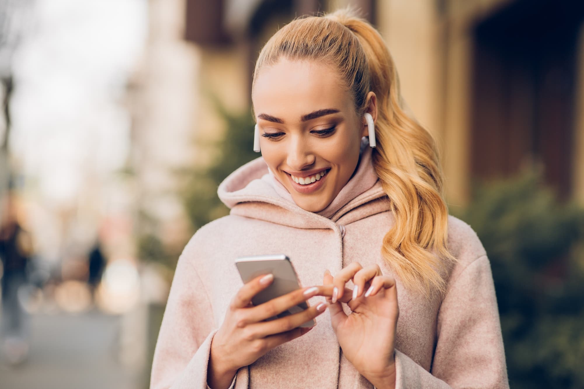 Happy woman texting outdoors on city street