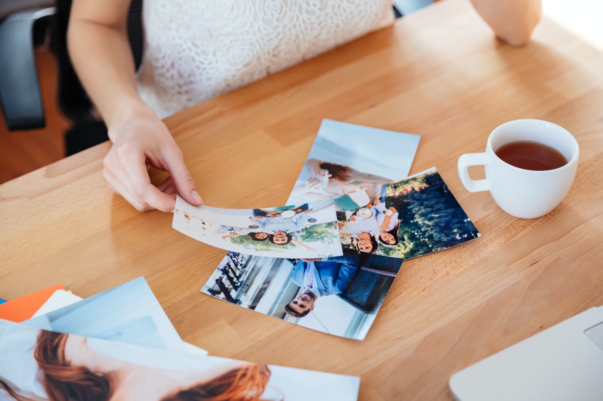 Table of young woman photographer drinking tea and choosing photos