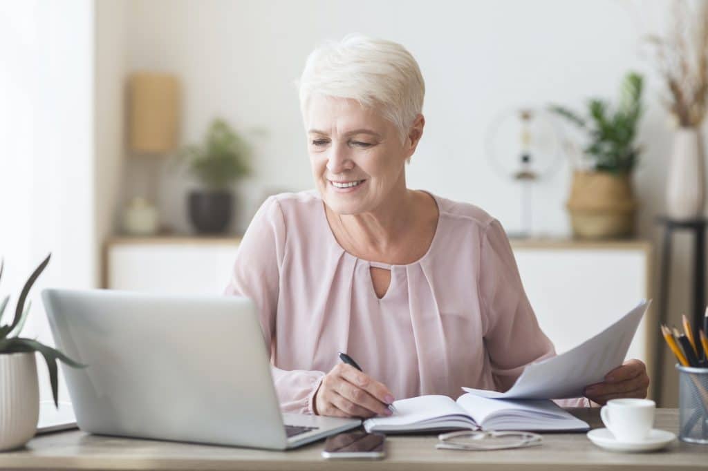 Cheerful senior business woman working with papers at home