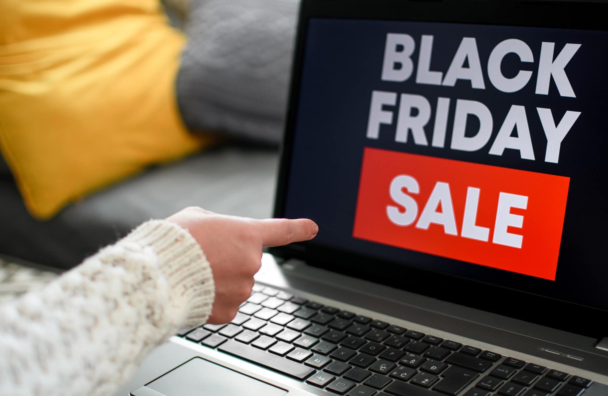 Woman pointing her finger toward a laptop screen with a black friday sale sign