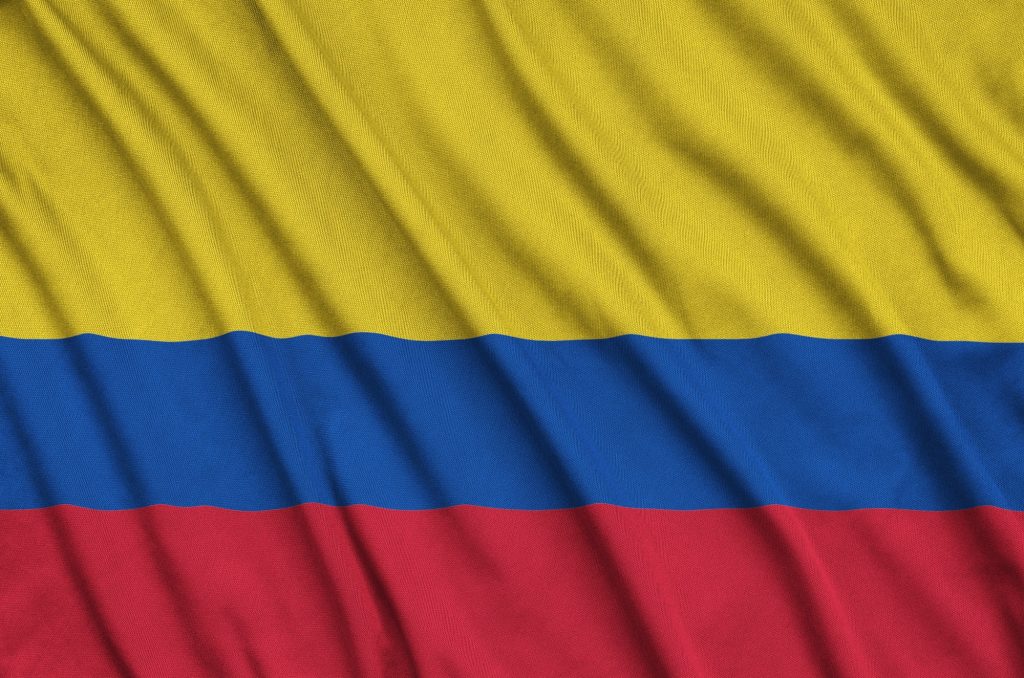 Colombia flag is depicted on a sports cloth fabric with many folds. Sport team waving banner