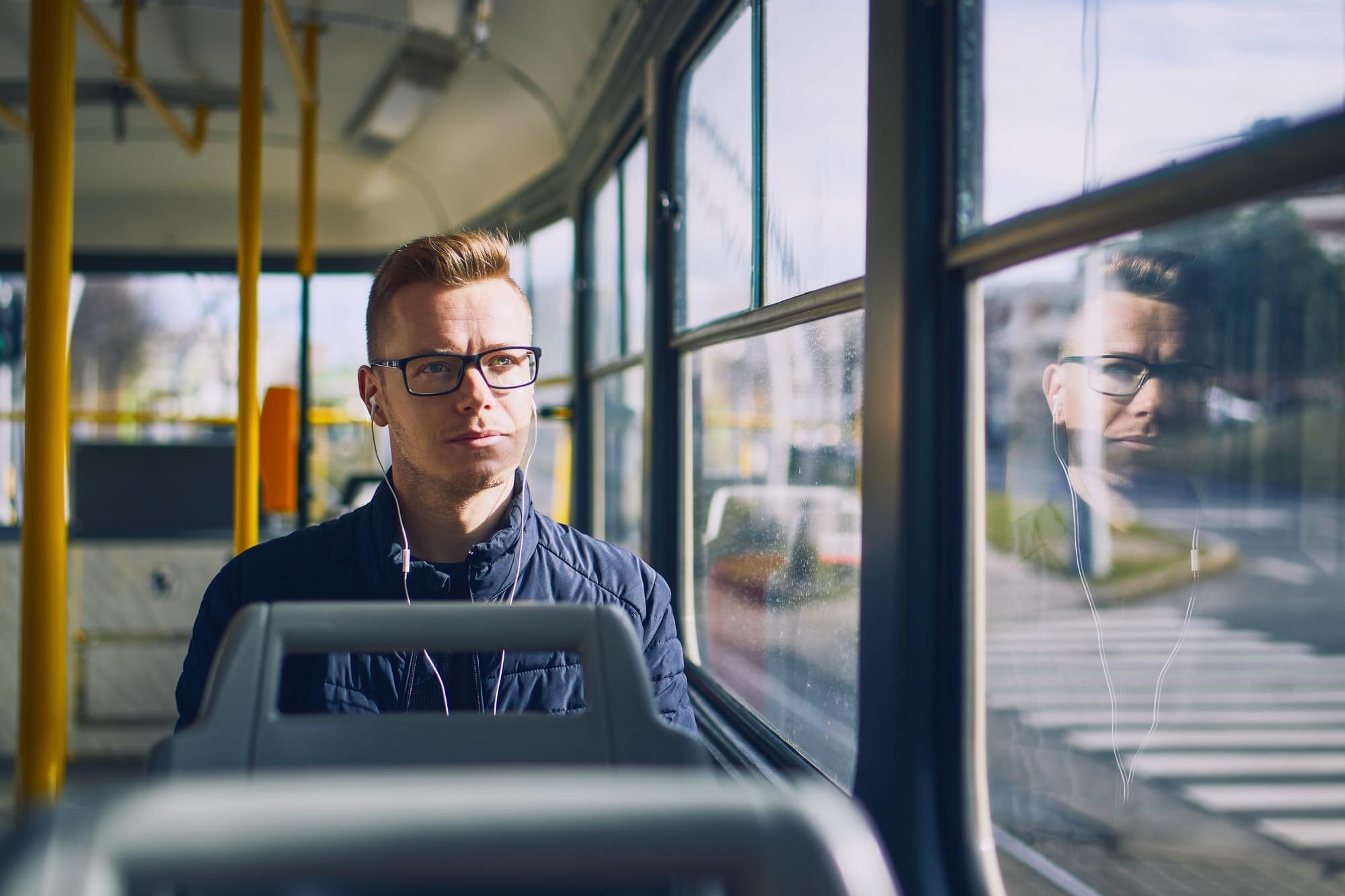 Young man listening music in tram. Travel by public transportation.