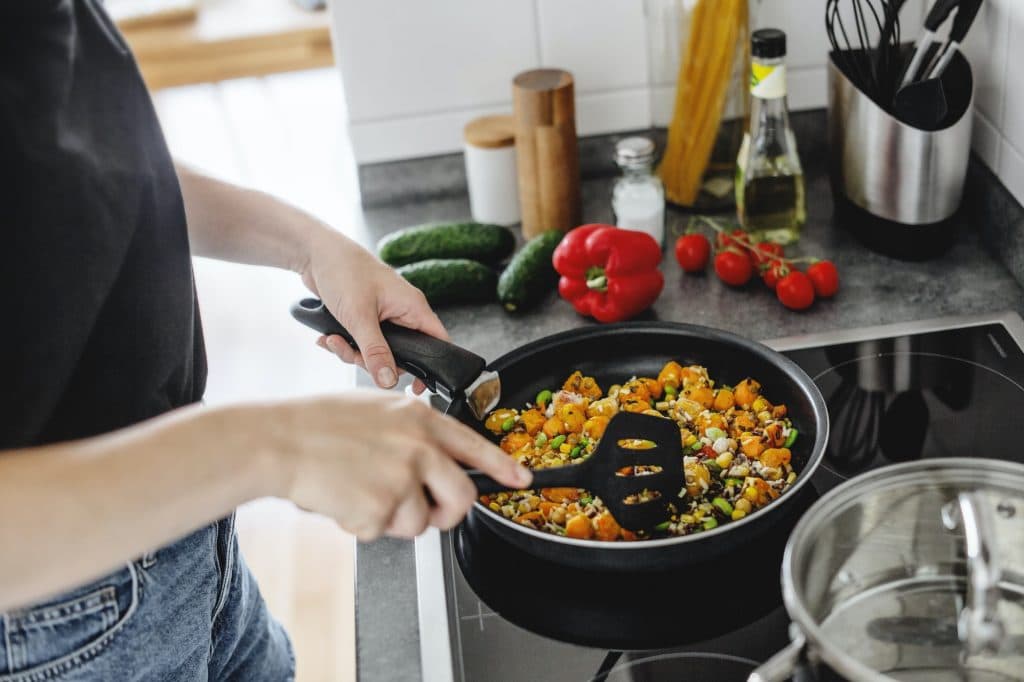 Young woman cooking vegetables at home kitchen