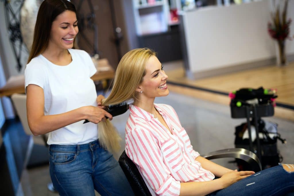 Hairdresser doing haircut for women in hairdressing salon