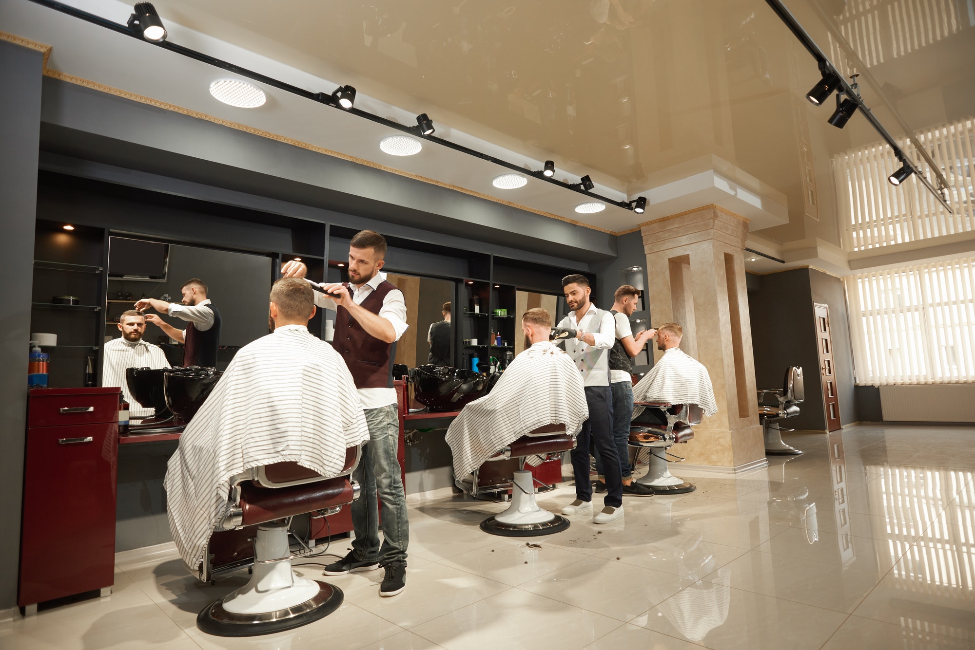 Male hairdressers servicing clients in barber shop