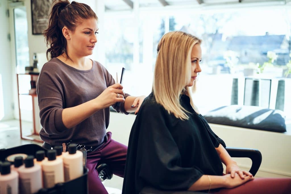 Young blonde woman getting her hair cut in a salon