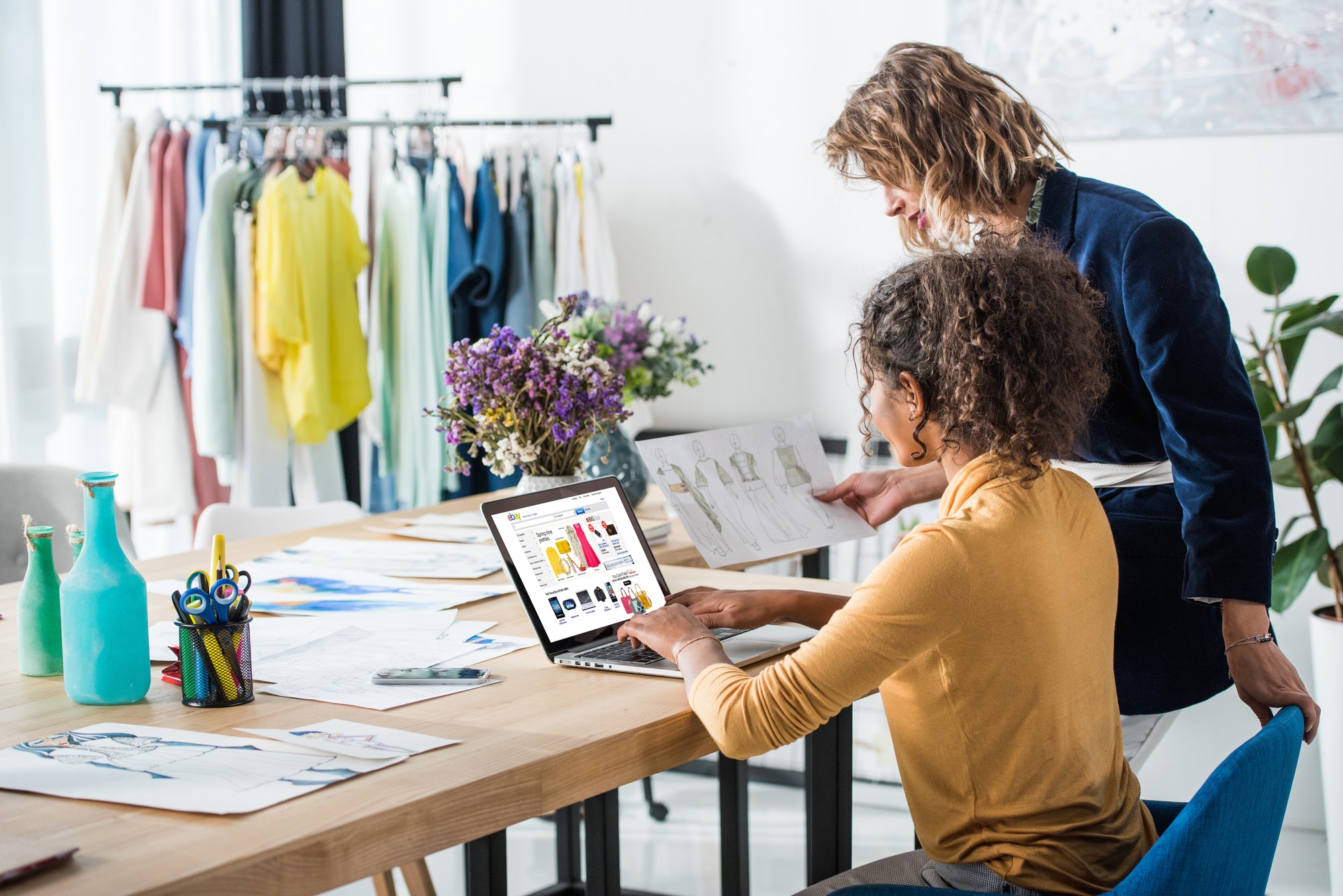 beautiful young multiethnic fashion designers using laptop at workplace