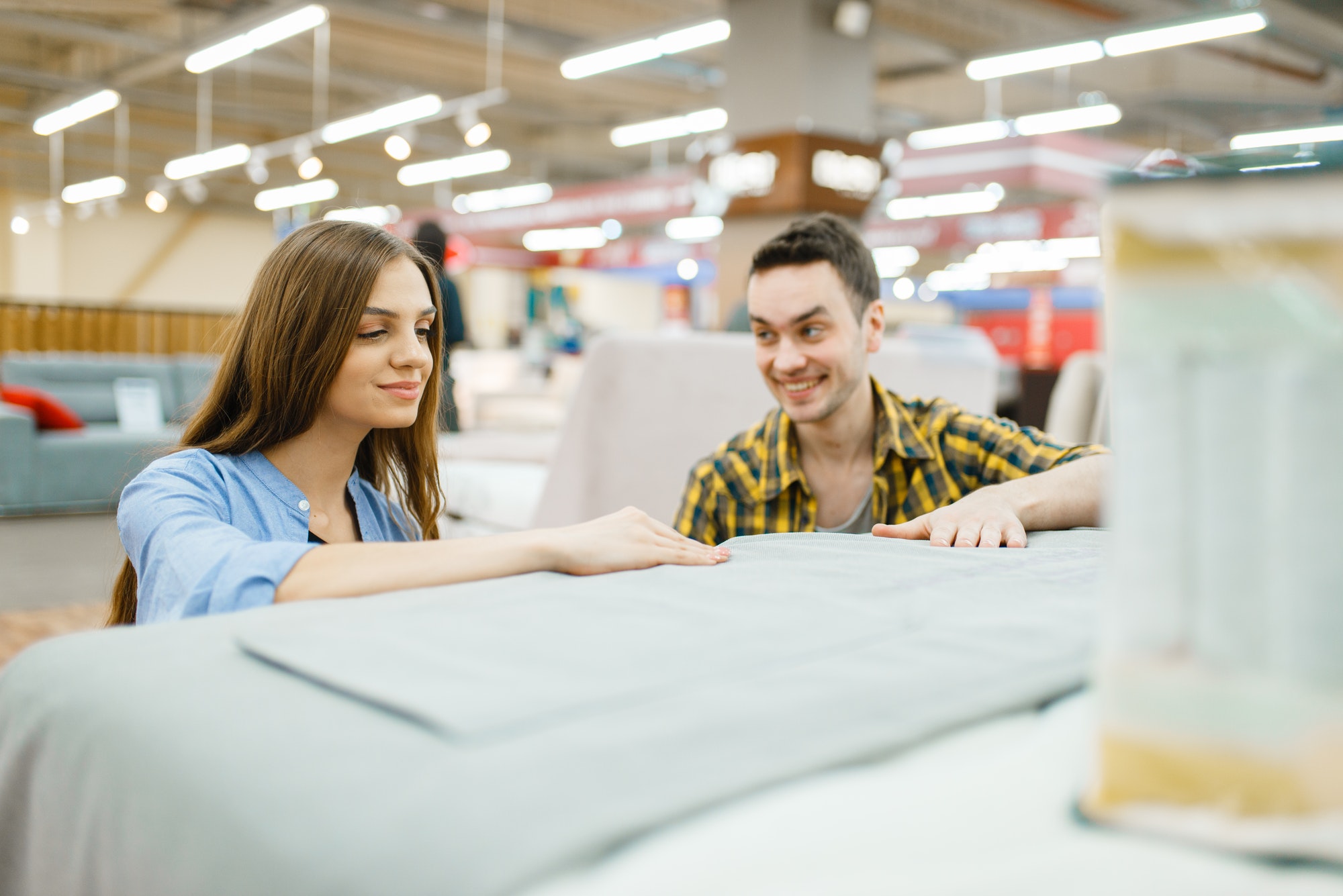 Couple buying blanket for bed in furniture store