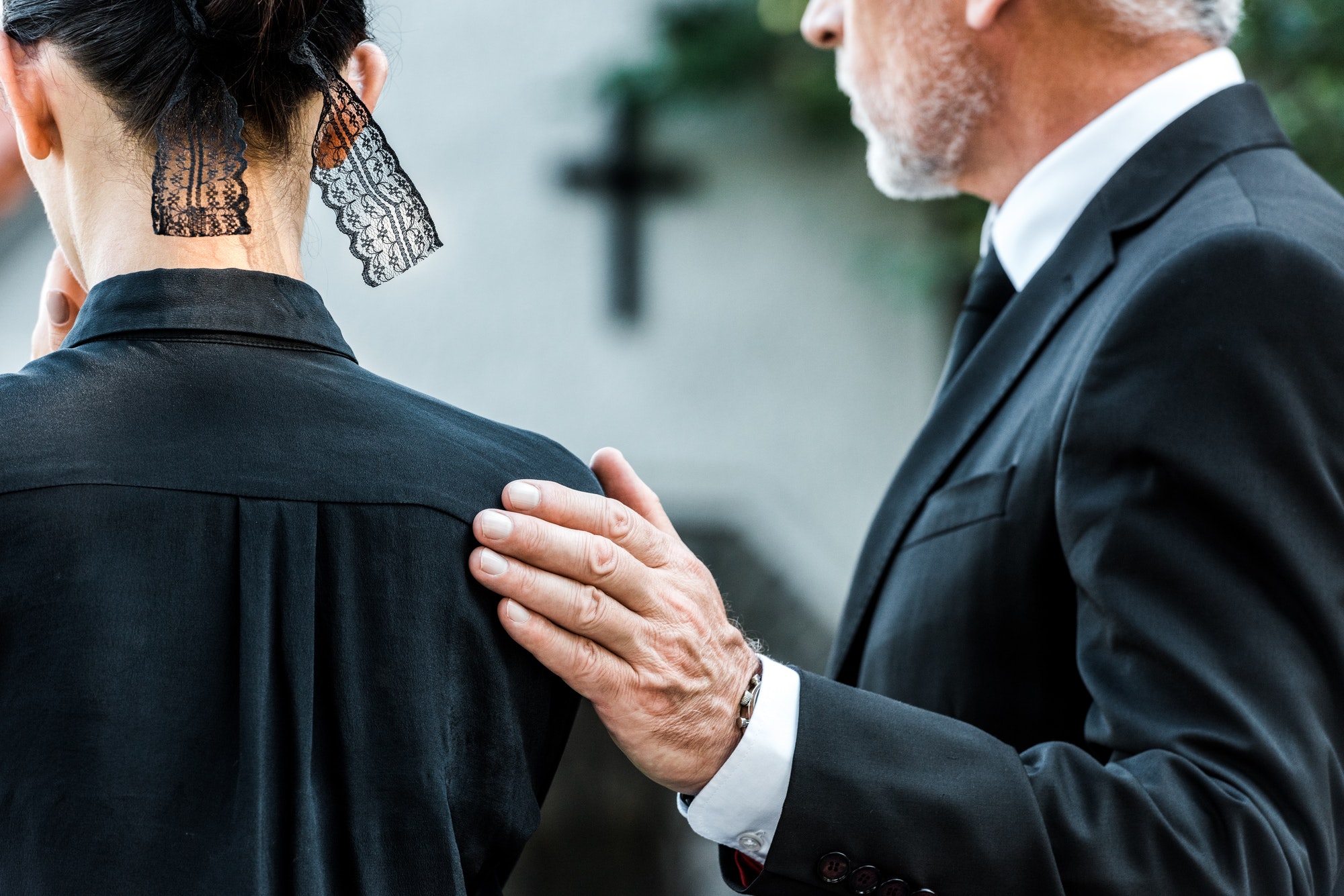 cropped view of man touching woman on funeral