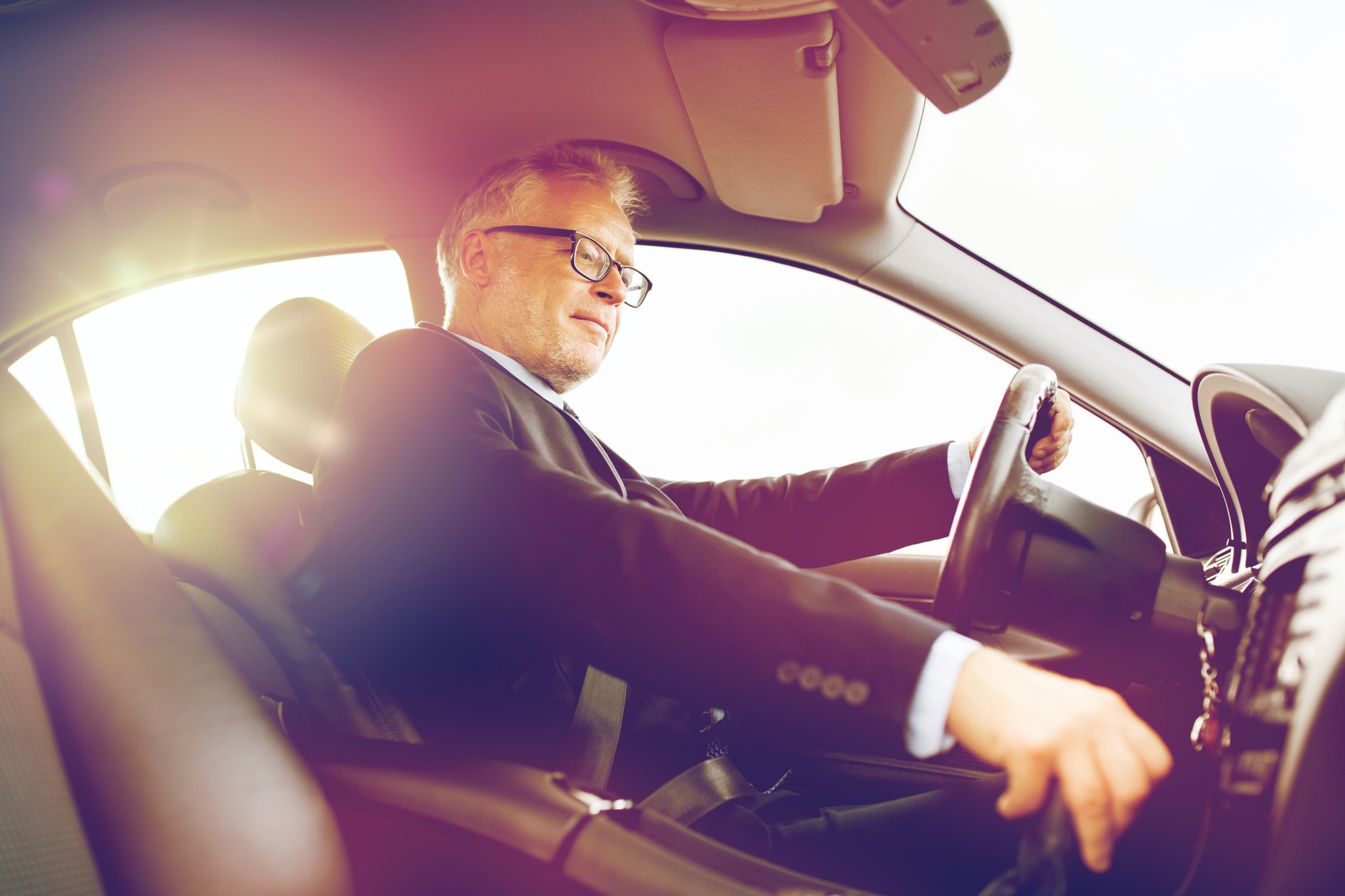 happy senior businessman driving car