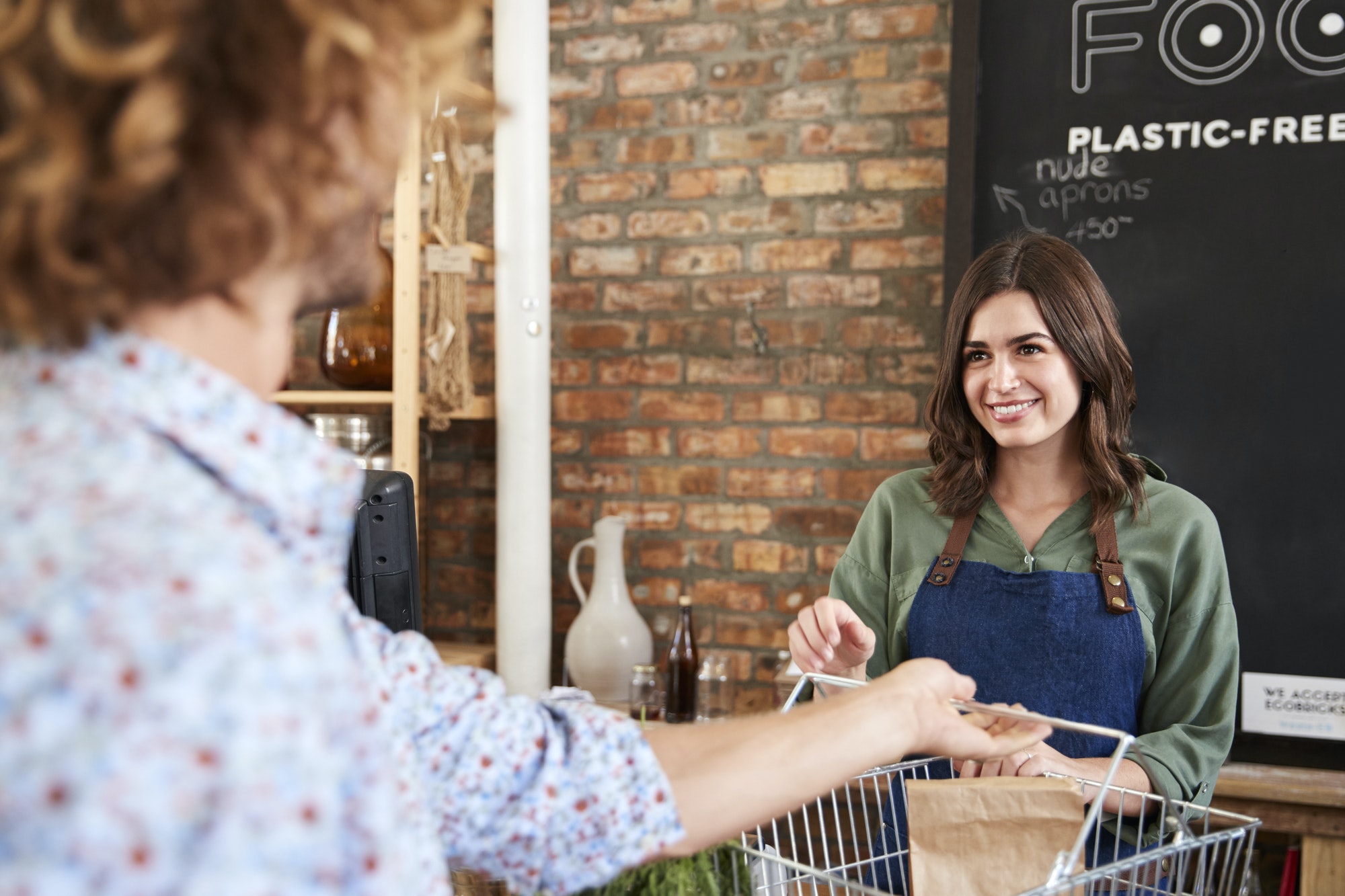 Customer Paying For Shopping At Checkout Of Sustainable Plastic Free Grocery Store