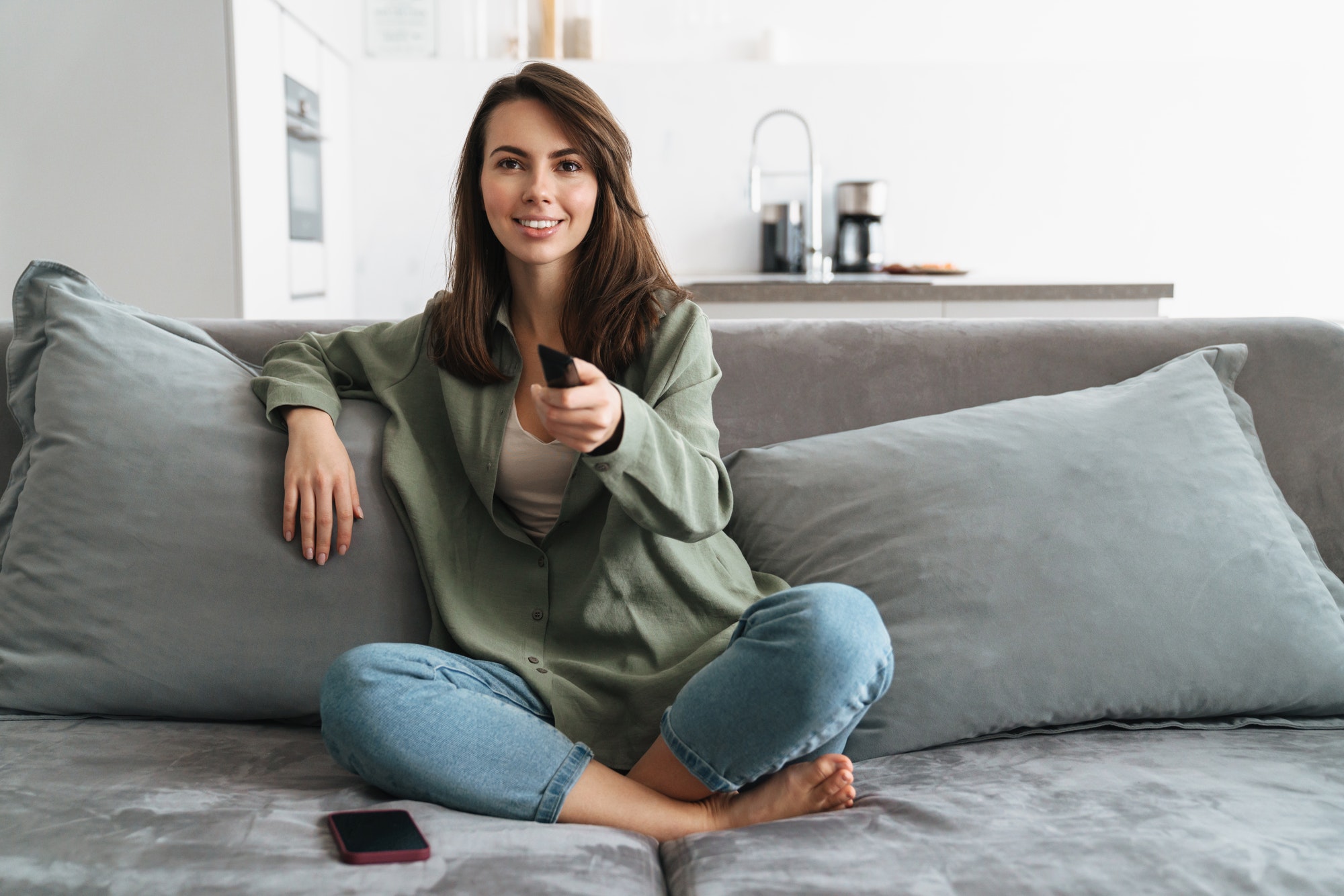 Happy young woman watching tv on sofa