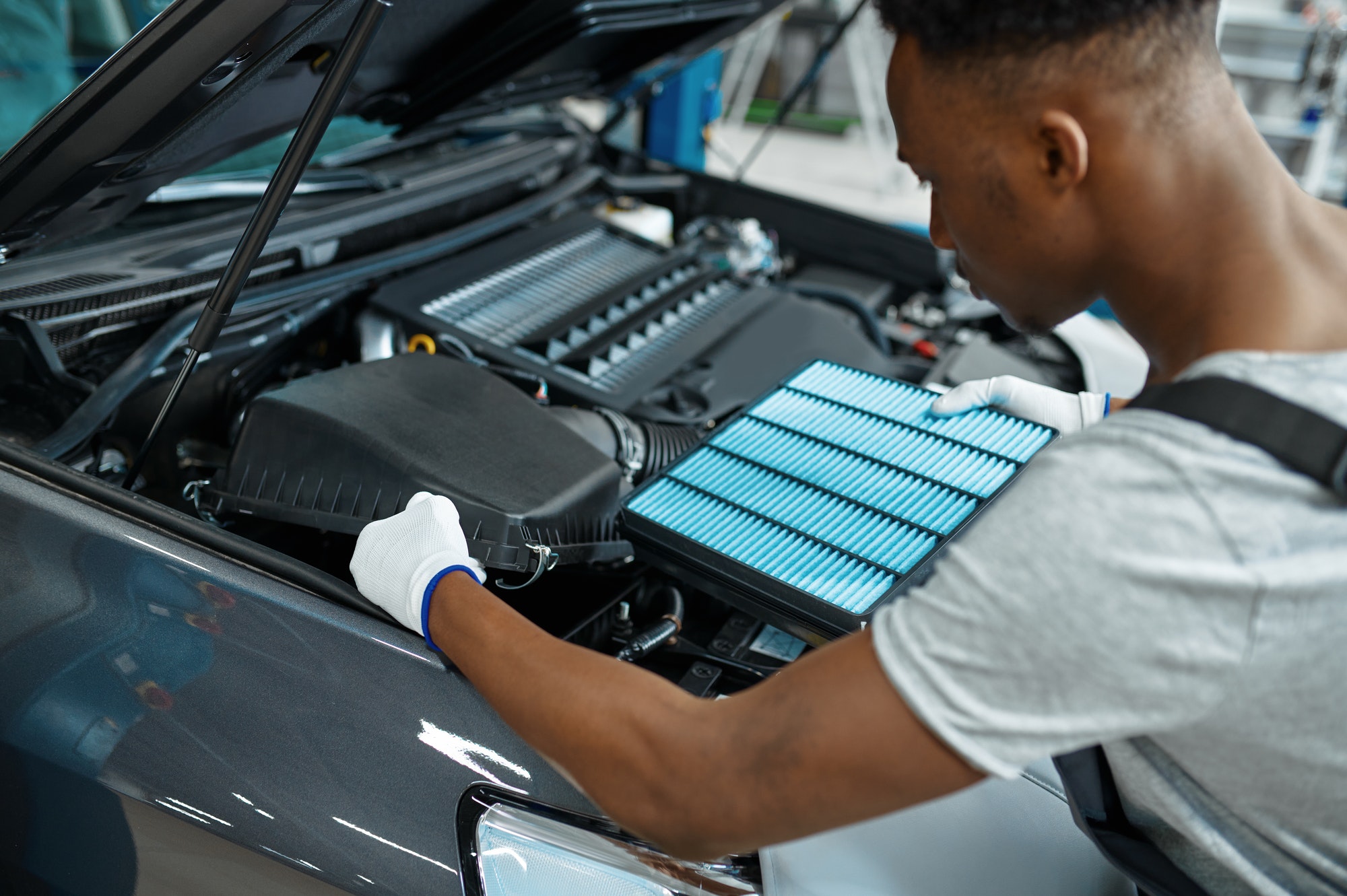 Male mechanic changes air filter, car service