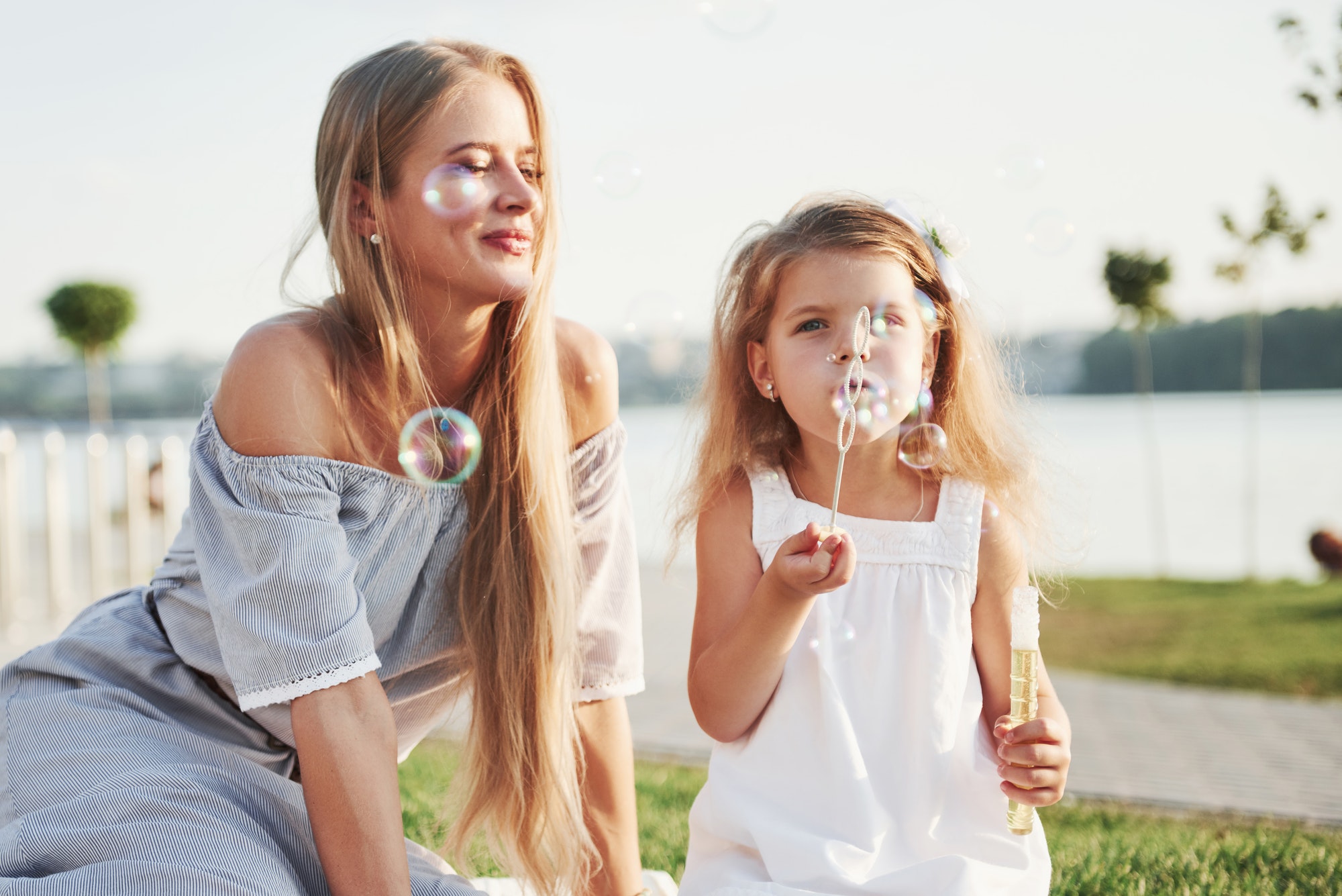 A wonderful girl child makes bubbles with her mom in the park