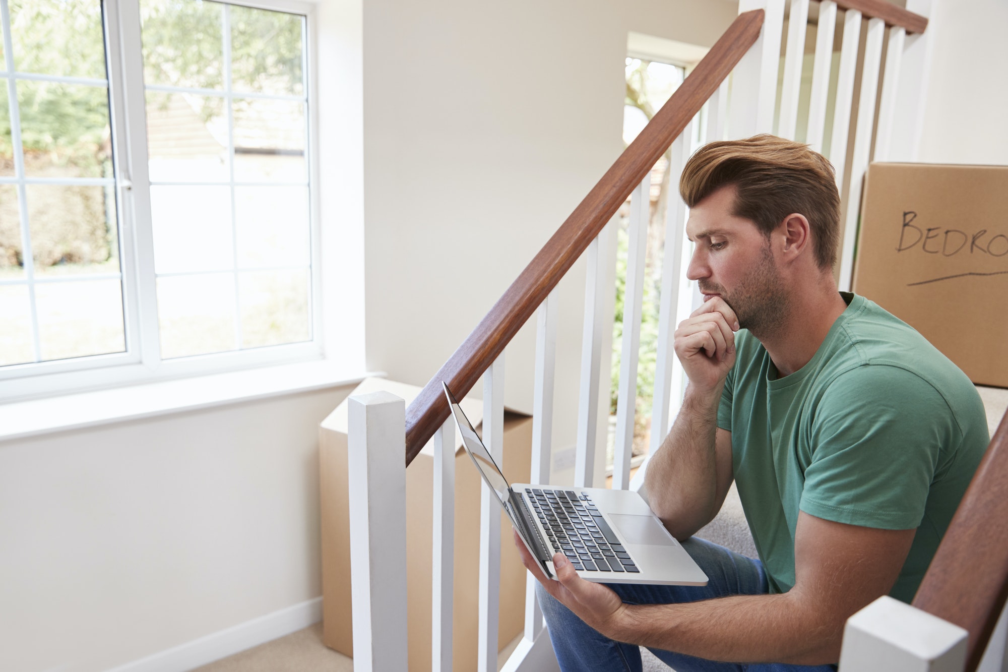 Man Moving Into New Home Looking At Personal Finances On Laptop