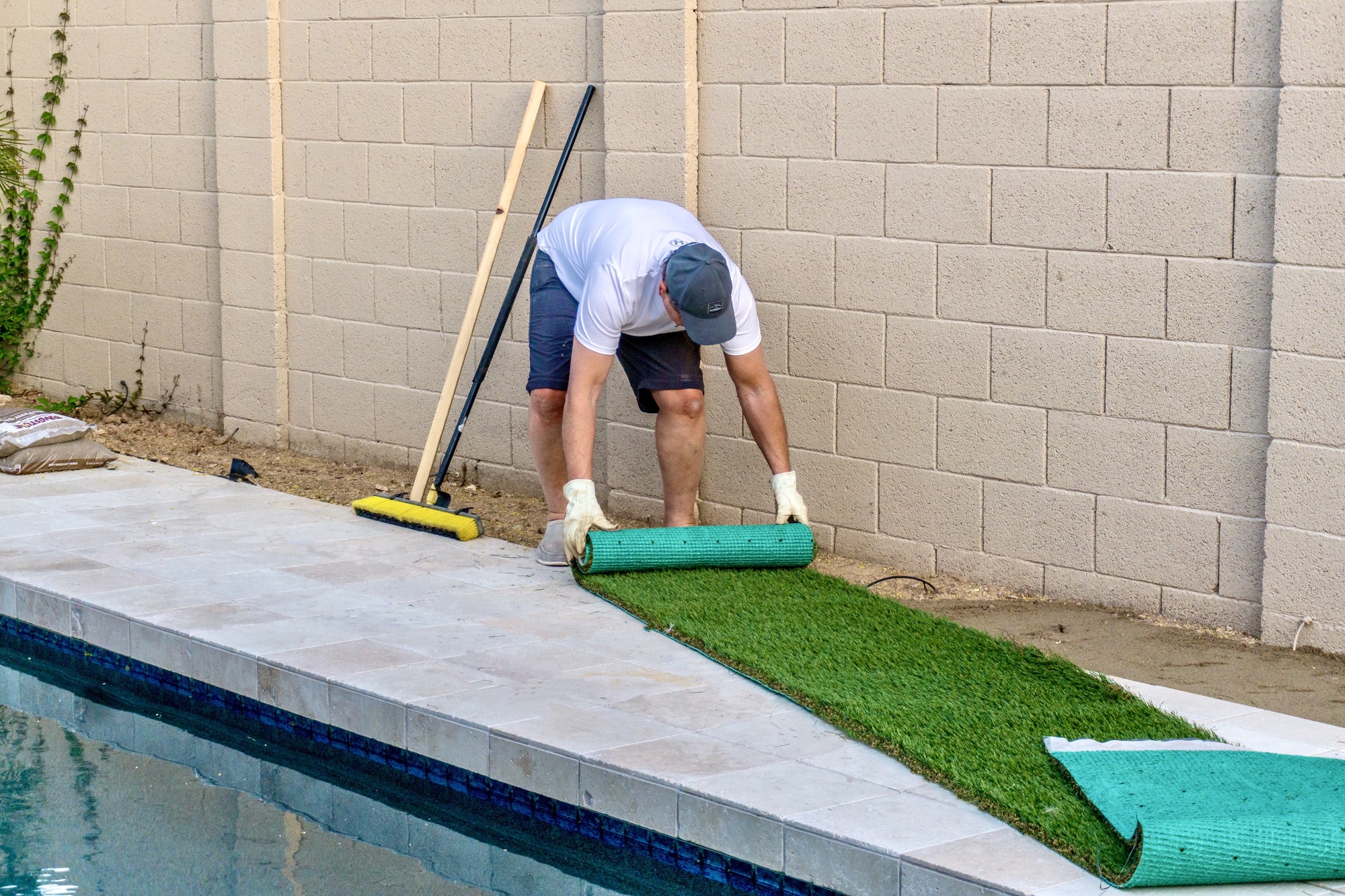 Adult male rolling out and installing artificial turf in a small space