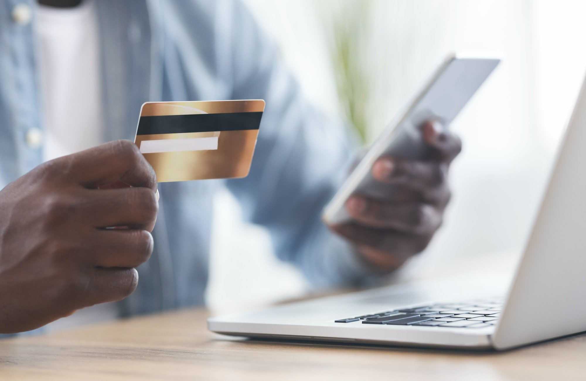 Black man using card and smartphone for paying bills online