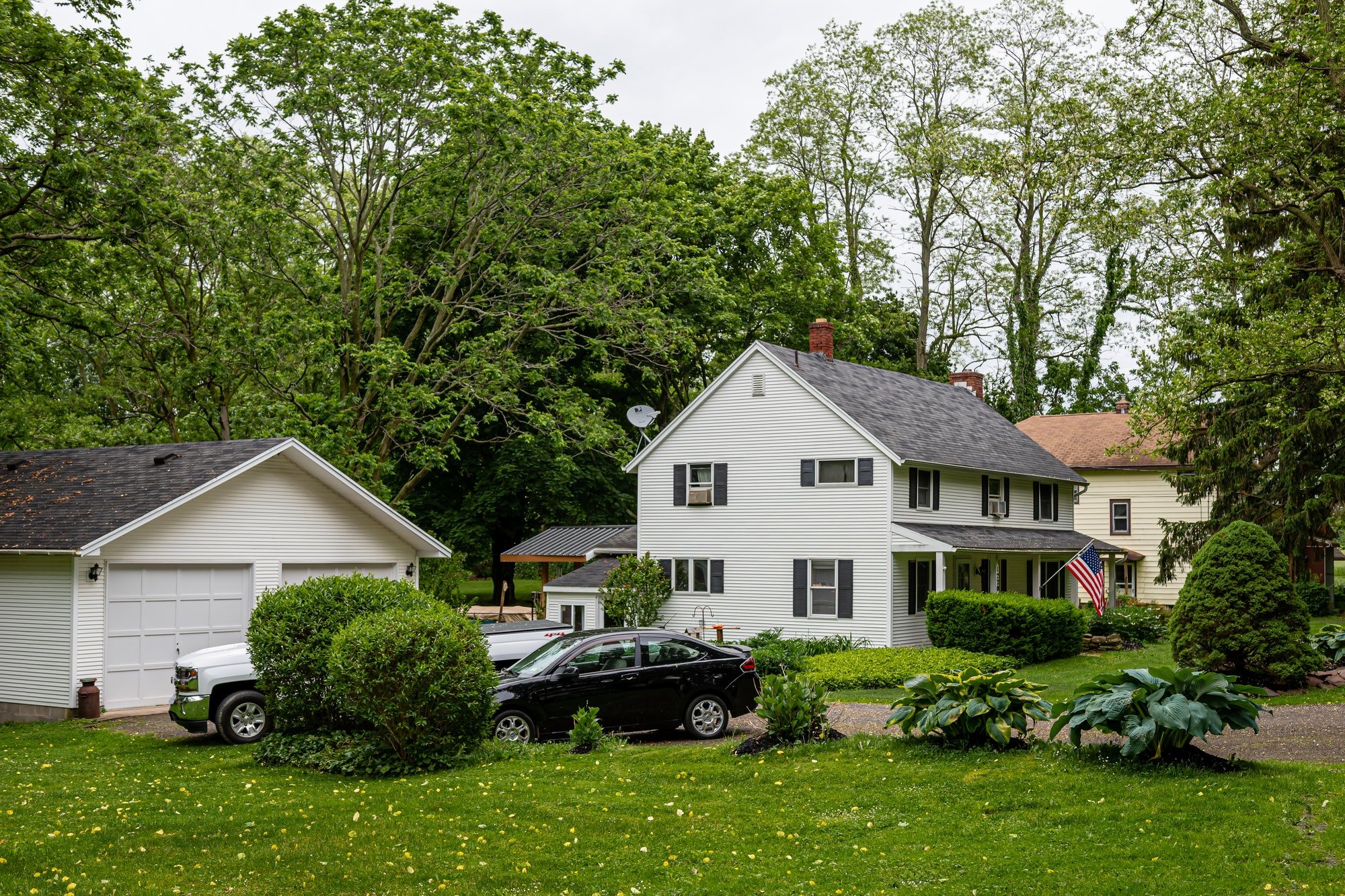 typical American residential house building with American flag and green lawn in front