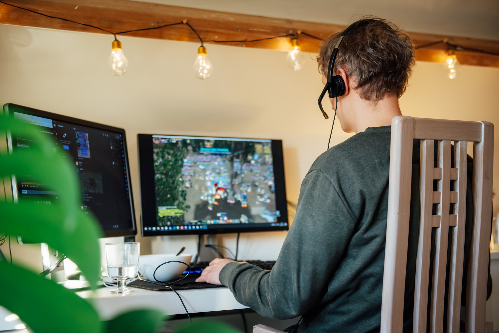 Back View man in a headset playing online games on his desktop pc