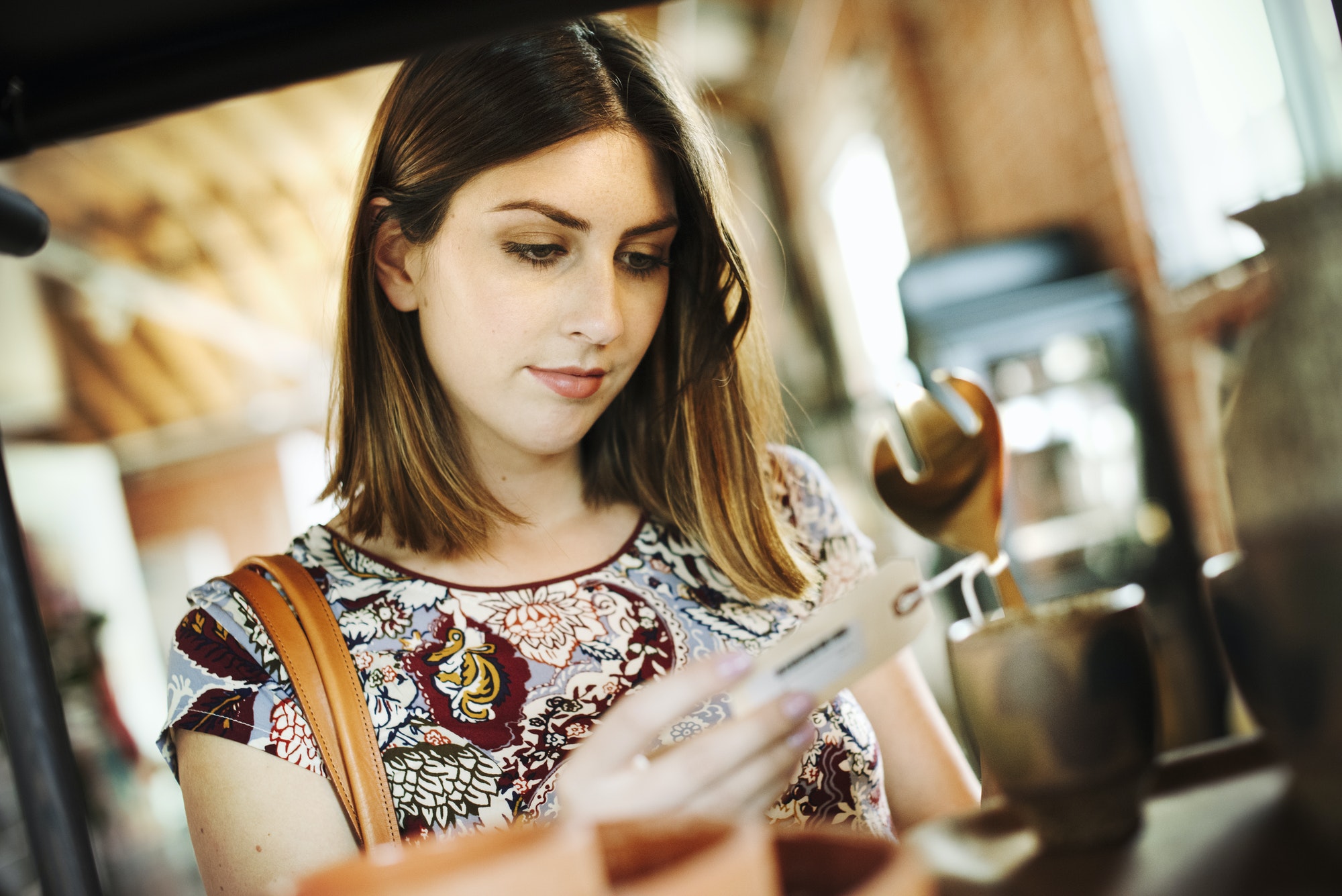 Young woman in a shop, looking at a price tag.