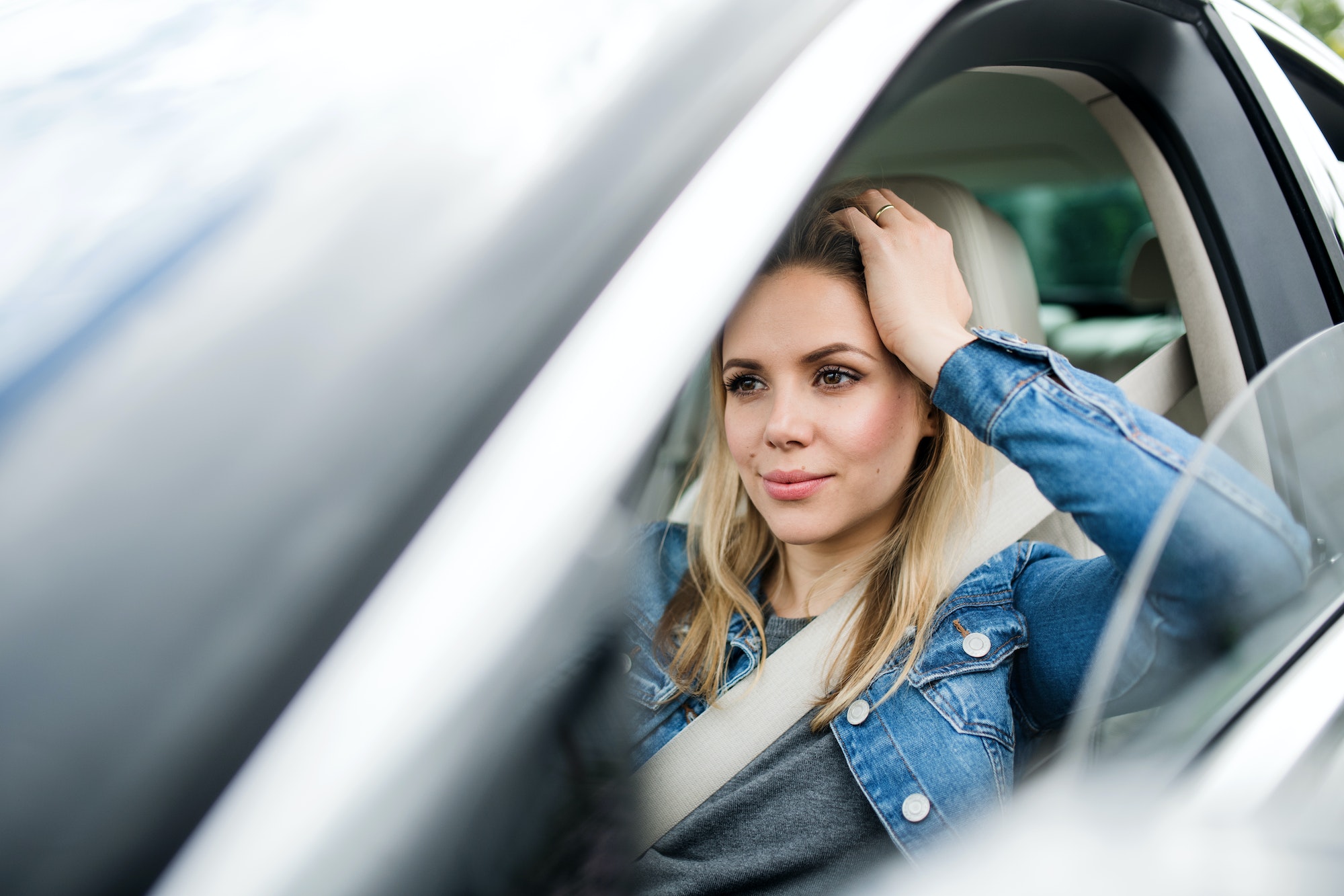 Young woman driver sitting in car, waiting.