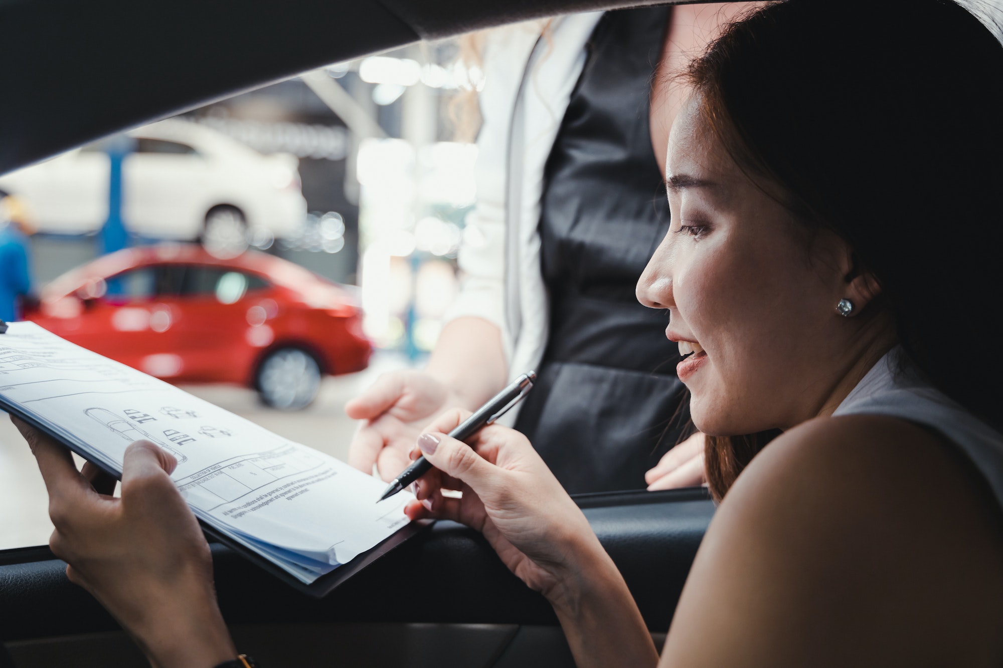 Woman signs the document in order to pick up the car from the car rental.